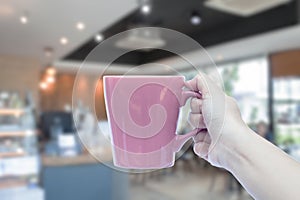 Women hand holding mug with blurred cafe