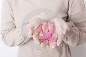 Women hand holding pink ribbon breast cancer on white background