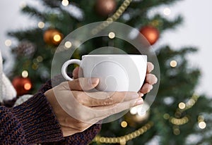 Women hand holding white ceramic coffee cup with light decoration. mockup mug for creative advertising text message content