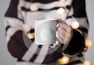 women hand holding white ceramic coffee cup with light decoration. mockup mug for creative advertising text message content