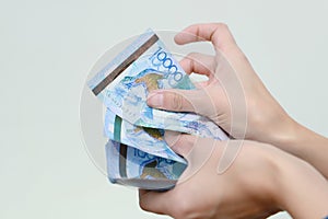 The women hand holds the national currency of Kazakhstan tenge