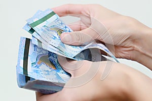 The women hand holds the national currency of Kazakhstan tenge