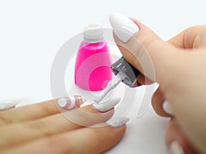 Woman painting long nails with a white nailpolish