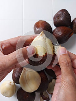 Women hand peeling salak fruit or snakefruit.  background in white