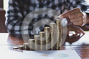 Women hand put money coins to stack of coins. Business Growth co