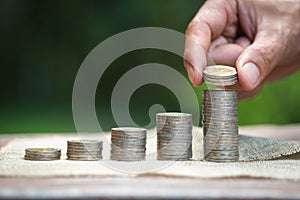 Women hand put money coins to stack of coins. Business Growth concept