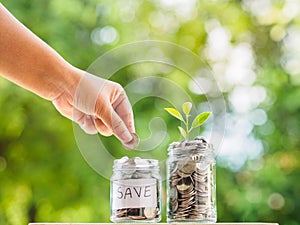 Women hand putting money coin into glass jar for saving money. s