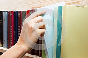 Women Hand selecting book from a bookshelf in