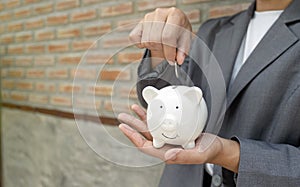 Women hand in suit putting coins into white piggy bank, step up start-up business to success, Saving money for future plan and