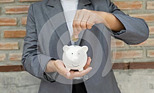 Women hand in suit putting coins into white piggy bank, step up start-up business to success, Saving money for future plan and