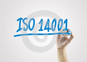 Women hand writing ISO14001 on gray background for business stra