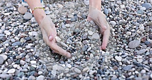 Women hands collect pebble stones on beach