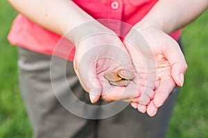 Women hands holding coins, the concept of business, natural green background in summer day