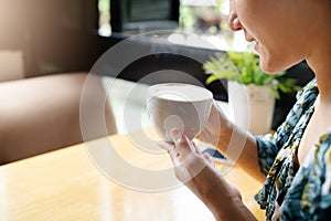 Women hands holding hot cup of coffee or tea in morning sunlight