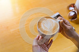 Women hands holding hot cup of coffee or tea in morning sunlight