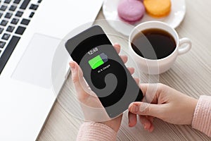 Women hands holding phone with charged battery screen on table