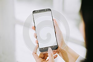 Women hands holding phone with screen on background of window