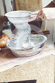 Women hands are holding sieve and sift flour