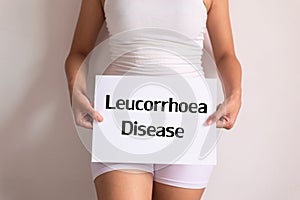 Woman hands holding a white sign with the word leucorrhoea disease on white background photo