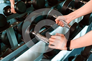 Women hands lifting dumbbells workouts with dumbbells in a gym. Sport women at fitness gym