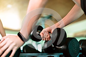 Women hands lifting dumbbells workouts with dumbbells in a gym. Sport women at fitness gym