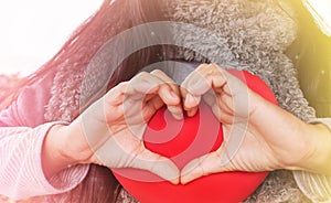 Women hands made heart shape on red heart