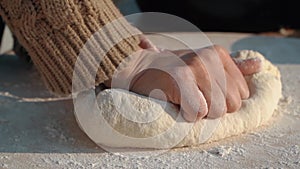 Women hands mixes the dough on a wooden board and make bread