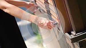 Women hands open outdoor wooden blinds closeup