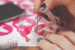 women hands with painted nails hold freshly cut pink peace dove decal that sticks to tip of curved weeding tool