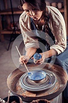 Women hands. Potter at work. Creating dishes. Potter& x27;s wheel. Dirty hands in the clay and the potter& x27;s wheel