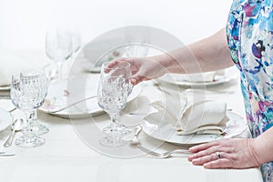 Women hands serving a crystal glassware of a table served with p