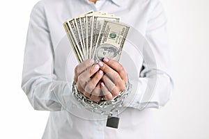 Women hands tied with chain hold one hundred dollar bills