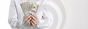 Women hands tied with chain hold one hundred dollar bills