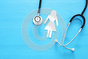 women healf Insurance . concept image of Stethoscope and female figure on wooden table. top view.