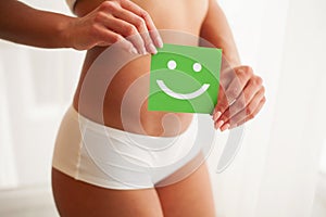 Closeup Of Healthy Female With Beautiful Fit Slim Body In White Panties Holding White Card With Happy Smiley Face In