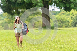 Women hiker or traveler with backpack adventure holding map to find directions and walking relax in the jungle forest outdoor for