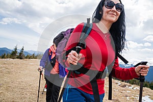 Women hikers with backpacks and nordic walking sticks