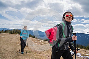 Women hikers with backpacks and nordic walking sticks