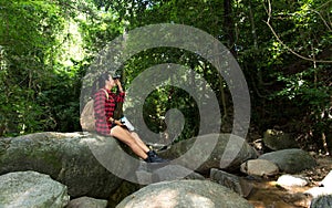 Women hikerwith backpack checks map to find directions and look binoculars in wilderness area at waterfalls and forest.