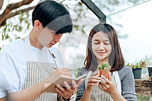 Women hold cactus and a man writing note in a book. Love couple enjoy hobby with darden cactus