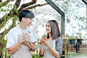 Women hold cactus and a man writing note in a book. Love couple enjoy hobby with garden cactus