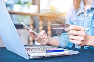 Women hold credit cards and use mobile phones to shopping online