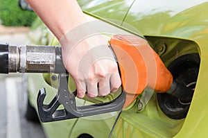 Women hold Fuel nozzle to add fuel in car at gas station