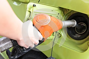 Women hold Fuel nozzle to add fuel in car at gas station
