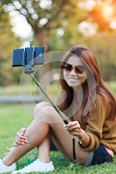 Women hold monopod use smart phone take photograph selfie in park