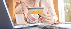 Women hold three credit cards to shop online with a laptop computer