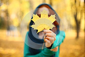 Women holding a leaf. girl holding a yellow maple leaf in autumn. Autumn leaves. selective focus