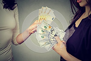 Women holding money exchanging with each other dollars to euro cash