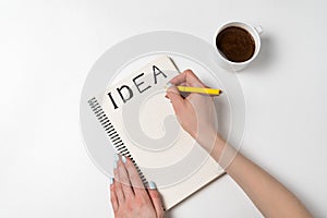 Women holding a pen writing in notebook idea. Notepad with ideas, cup of coffee on a white background