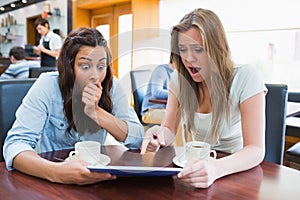 Women holding a tablet and looking surprised